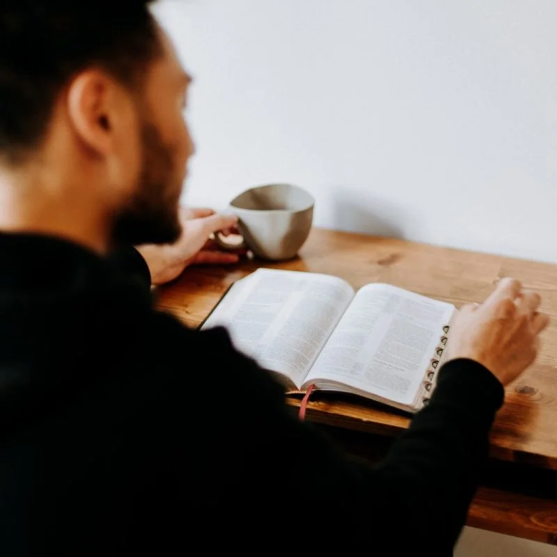 man in black long sleeve shirt writing on white paper