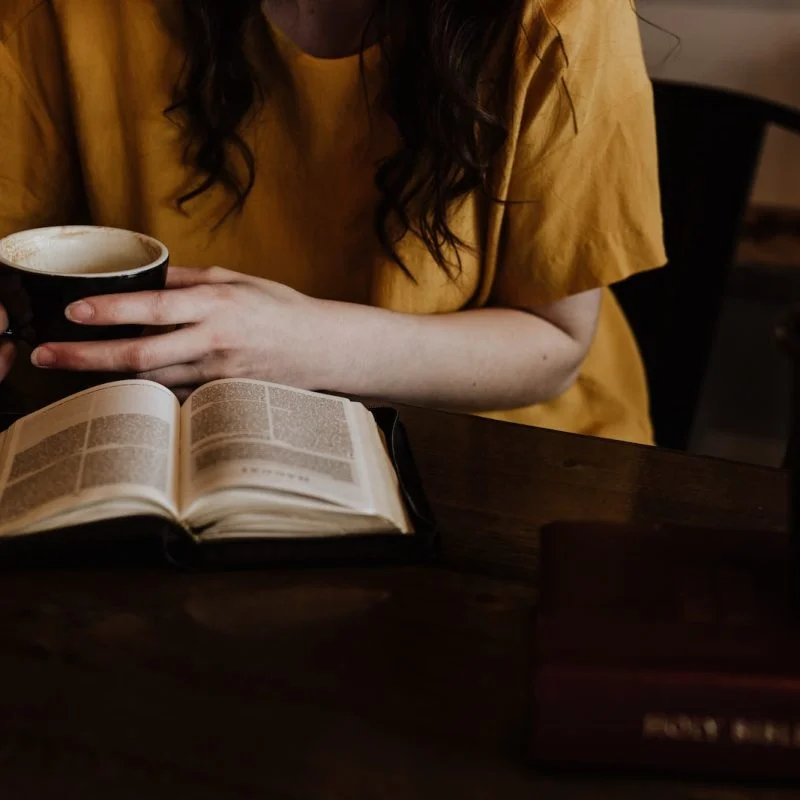 woman holding mug in front of book