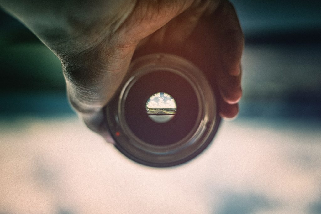 person holding camera lens viewing mountains