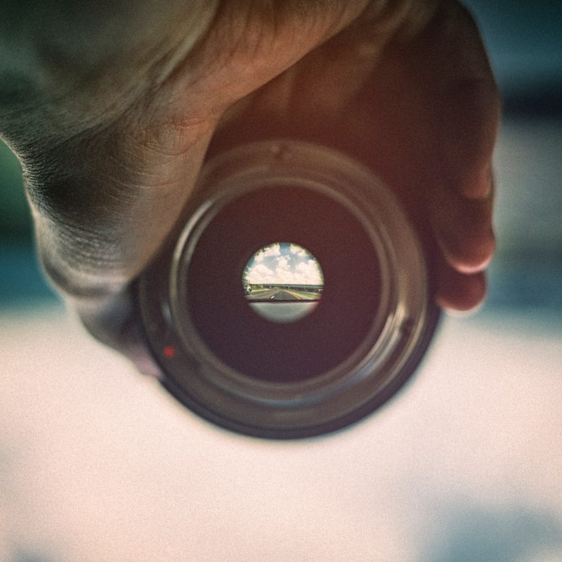 person holding camera lens viewing mountains