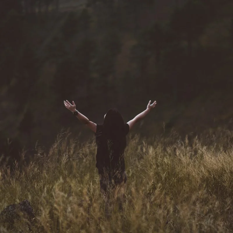 man raising arms between greenfield