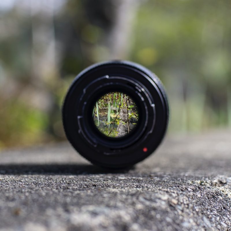black DSLR camera lens on concrete surface