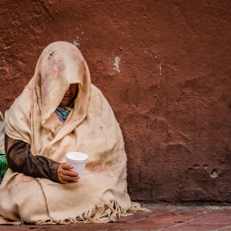 person in scarf holding white disposable cup