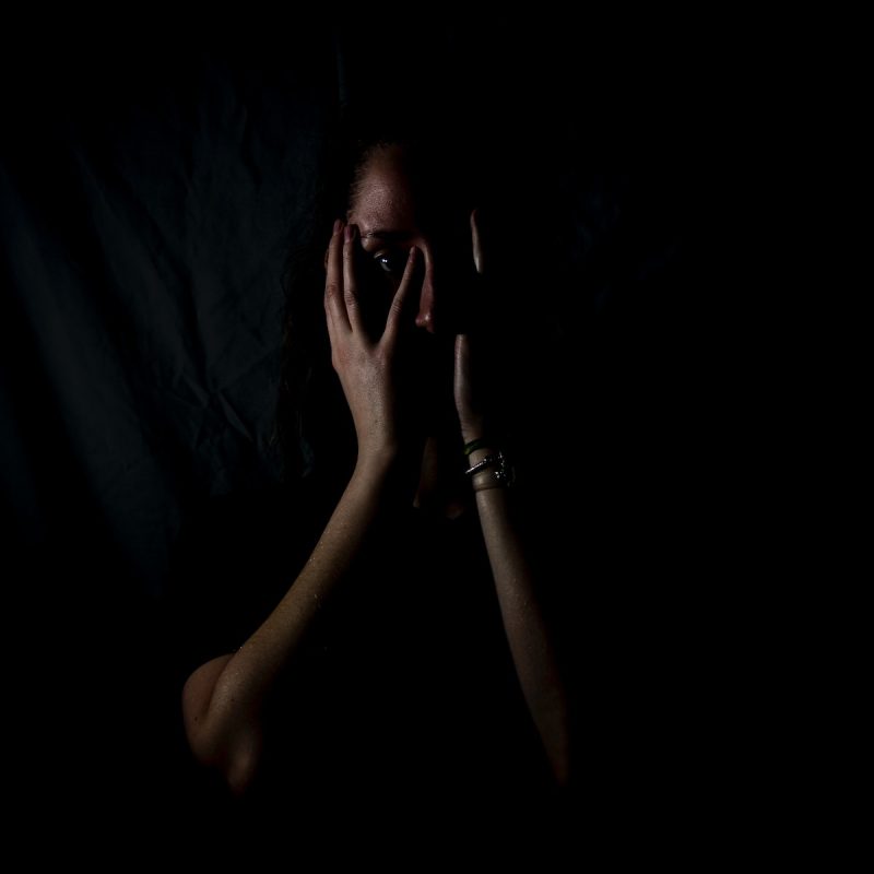 woman holding her face in dark room