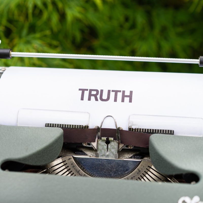 a close up of a typewriter with the word truth on it