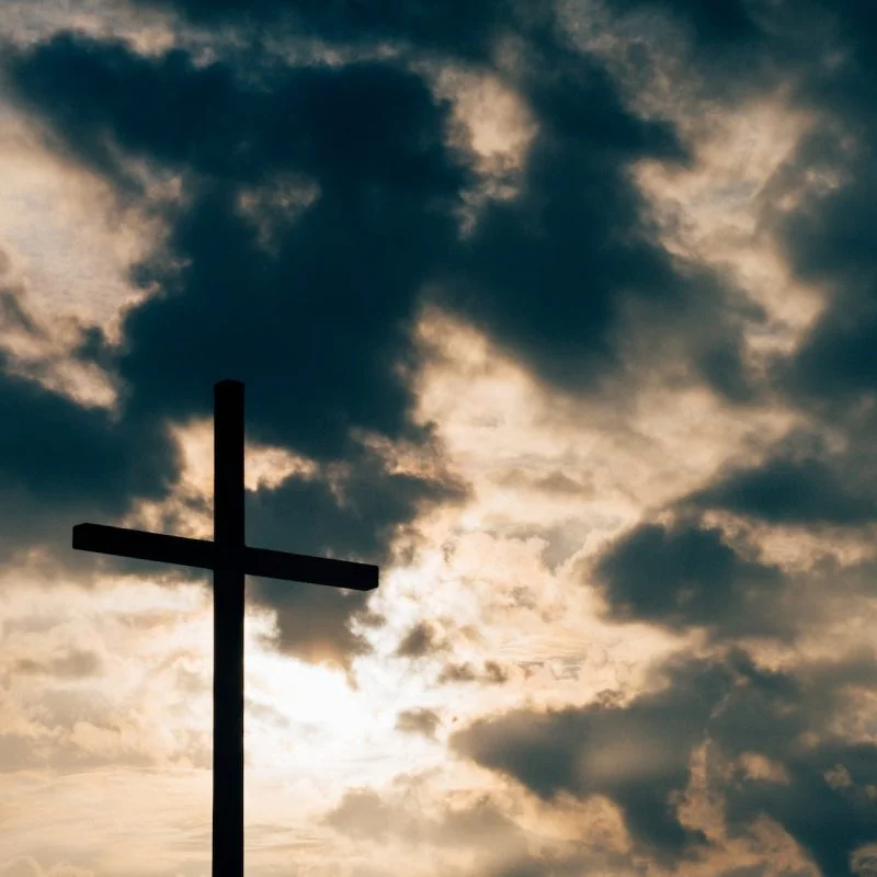 silhouette of cross under cloudy sky