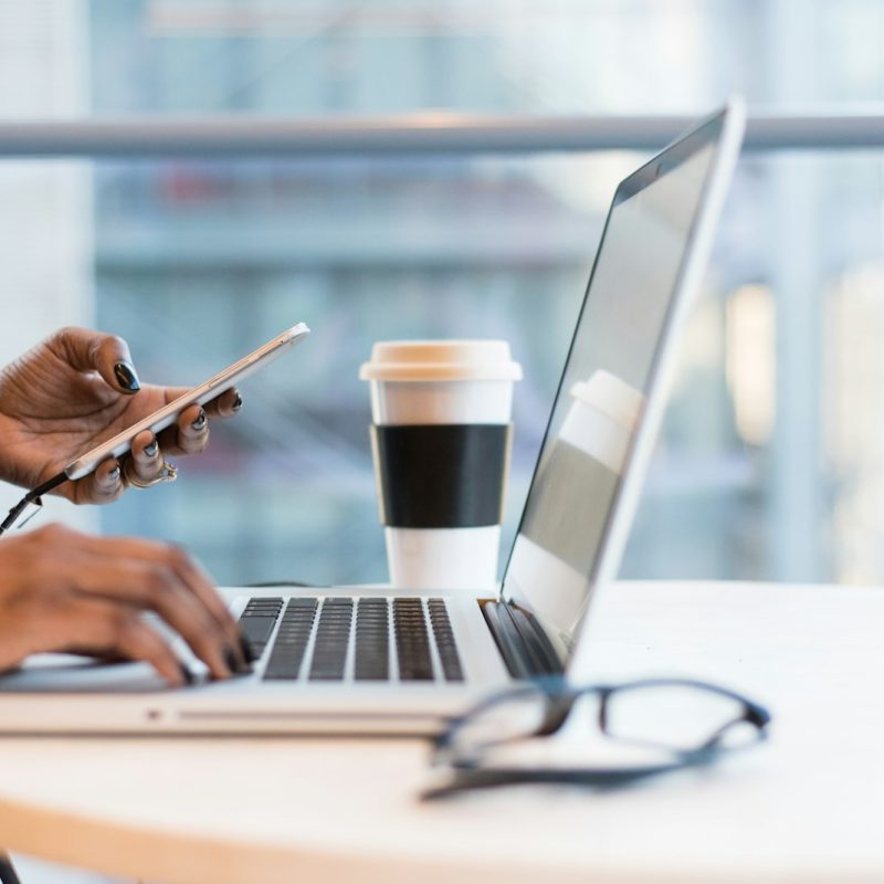 person using smartphone and MacBook