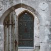 opened gray wooden door with closed green wooden door at the distance