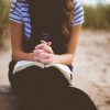 woman sitting on brown bench while reading book