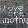 love one another chalk written on concrete floor