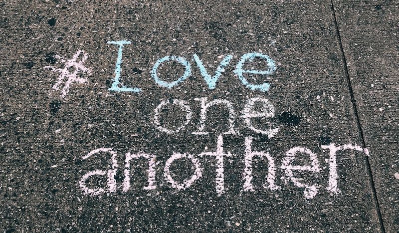 love one another chalk written on concrete floor