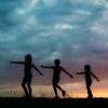silhouette of 2 women jumping on grass field during sunset
