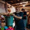 a man standing next to a green bucket filled with food